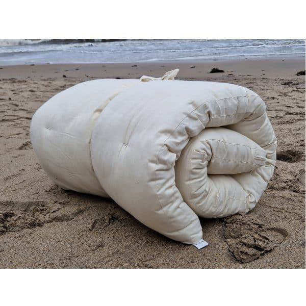Travelfuton tunn rese futonmadrass fran Polonia natural design fyrkantig ihoprullad pa stranden scaled